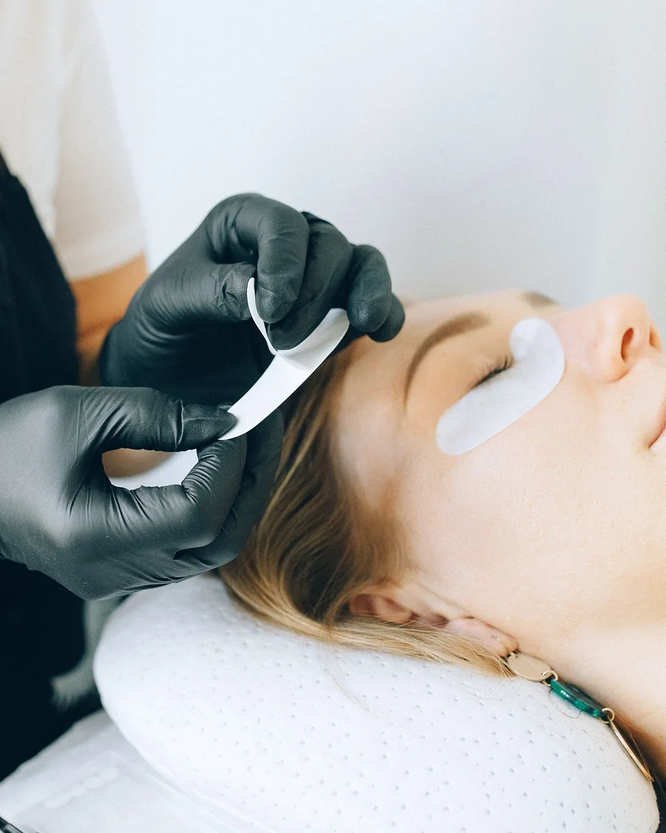 Une technicienne réalise une pose d'extensions de cils