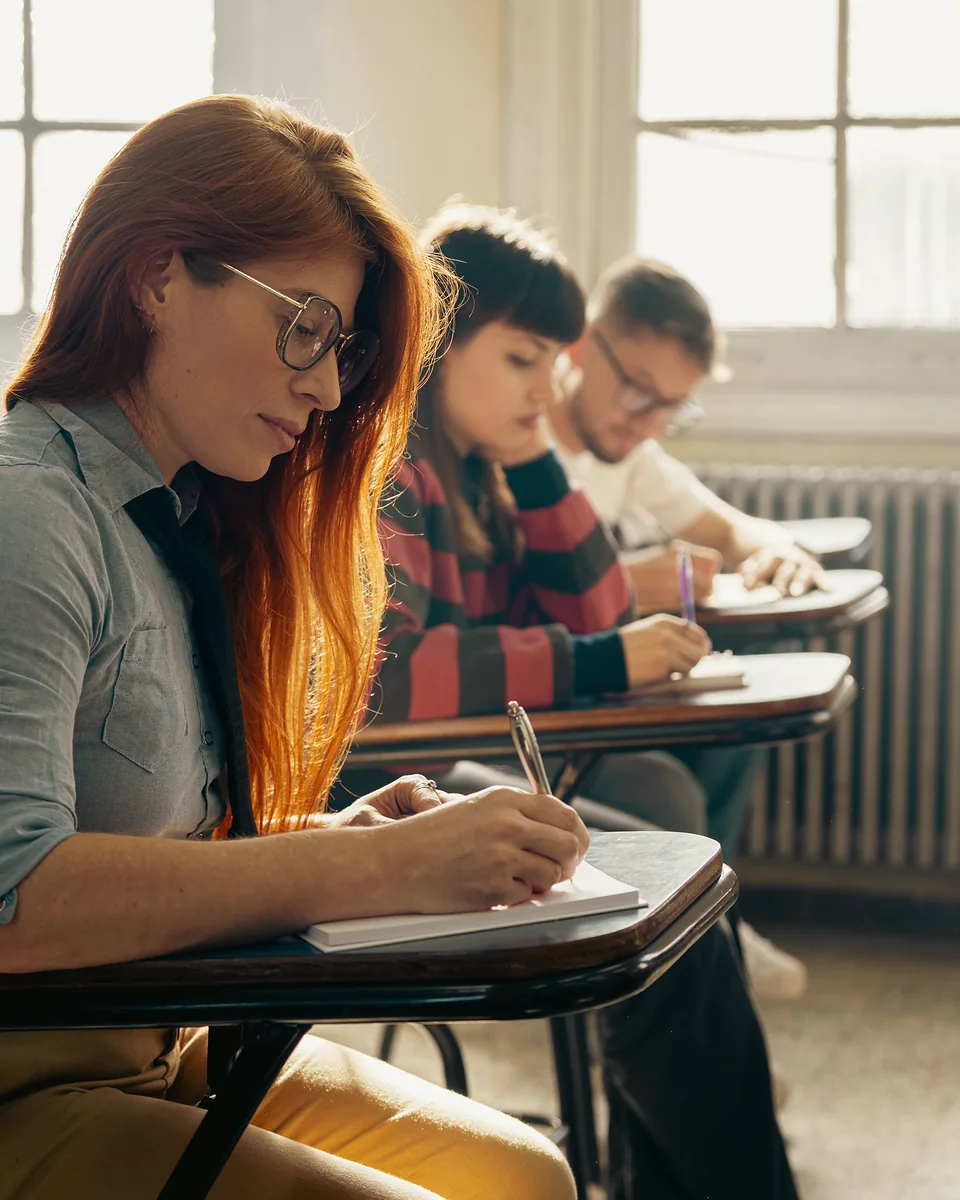 Des apprenants prennent des notes en classe, à la lumière du jour
